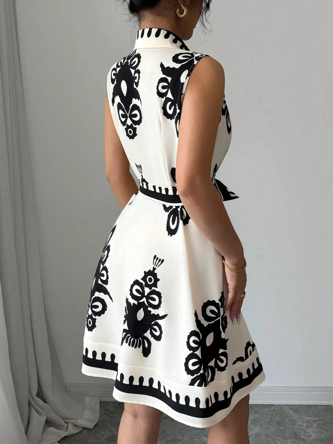 White dress with black geometric patterns worn by a person against a neutral background