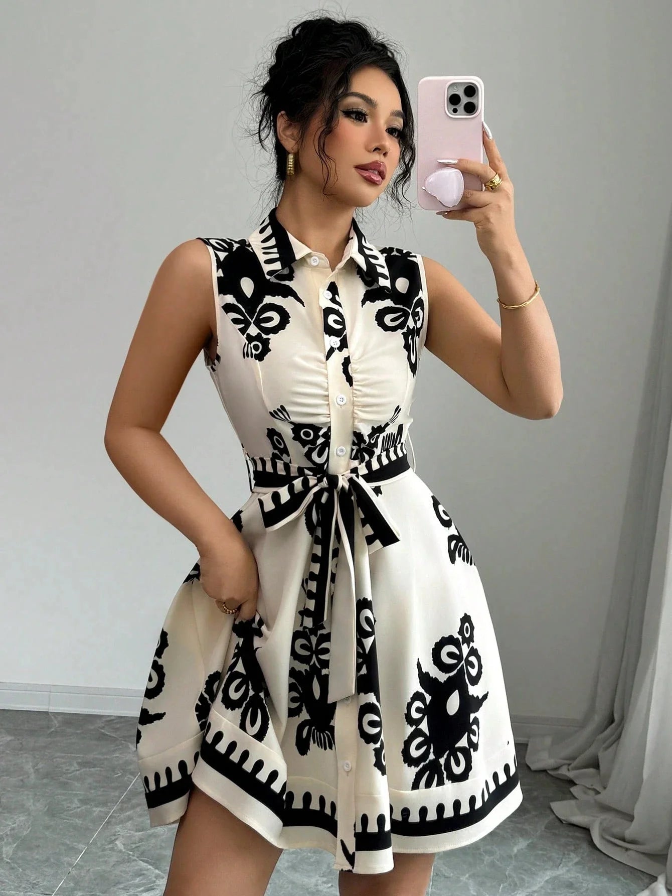 Woman taking a mirror selfie wearing a black and white patterned dress.