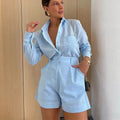 Woman wearing a light blue outfit with a matching shirt and shorts against a neutral background.