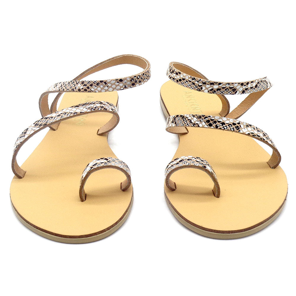 Pair of gold sandals with snake print straps on a white background