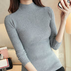 Person wearing a gray ribbed sweater with a blurred indoor background
