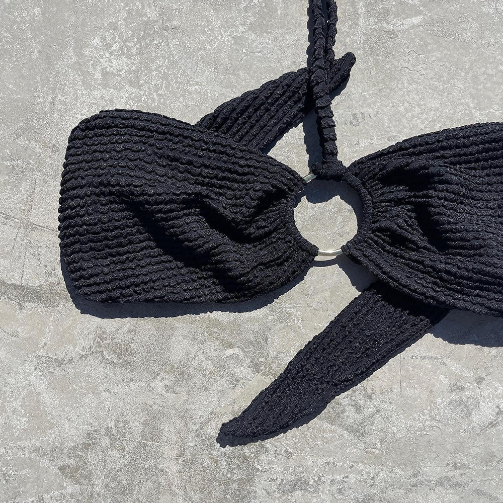 Black knitted bikini top with a bow detail on a gray surface