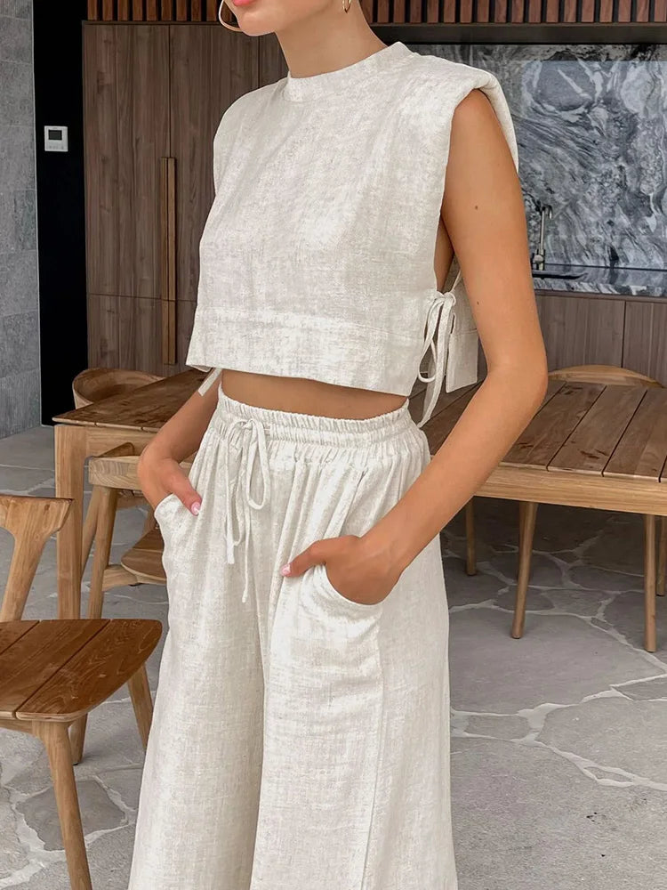 Person wearing a white sleeveless top and wide-leg pants in an outdoor setting.