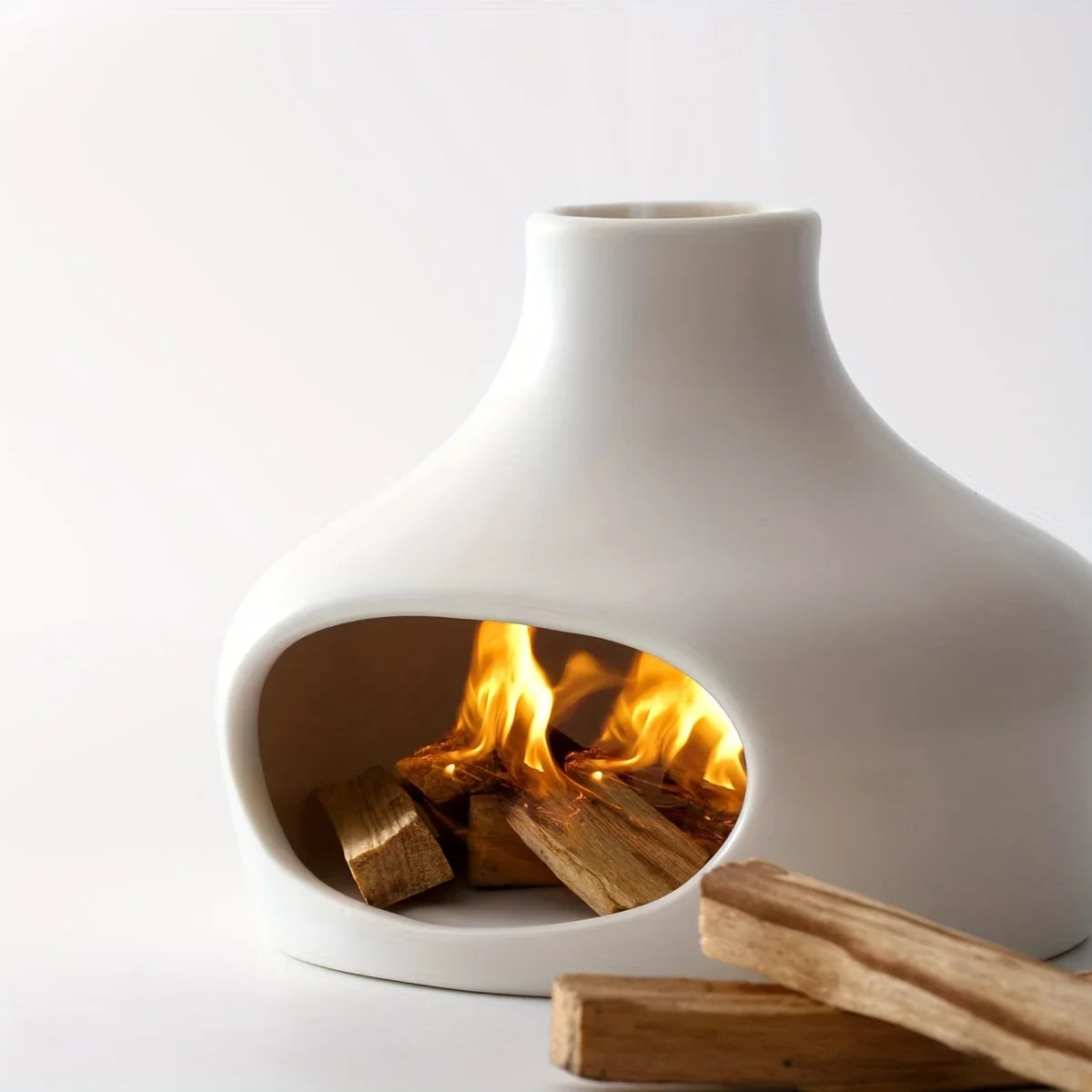 White ceramic fireplace with burning wood inside on a white background