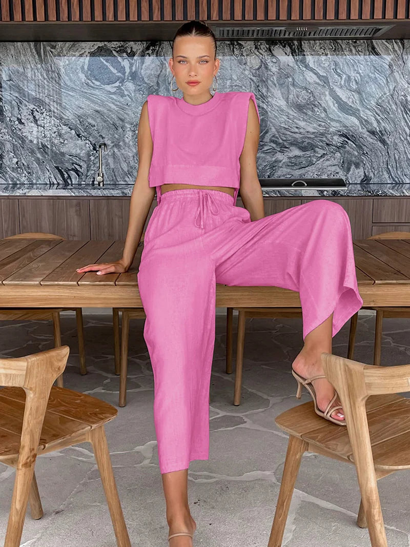 Woman in a pink outfit sitting on a wooden table with a marble wall in the background