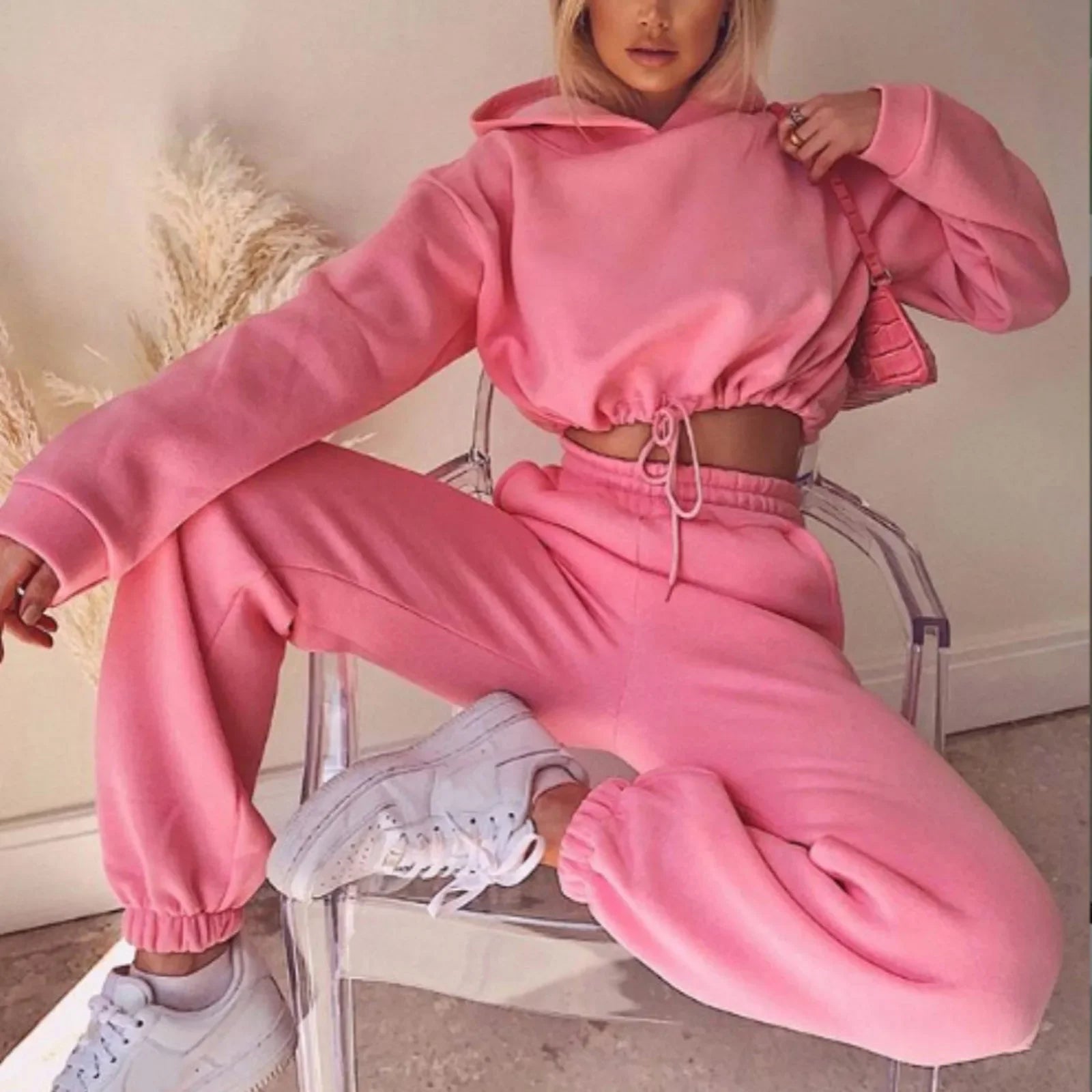 Person wearing a pink tracksuit sitting on a chair.