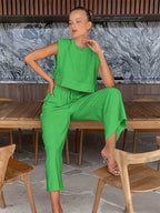Woman in a green outfit sitting at a wooden table with a marble wall in the background