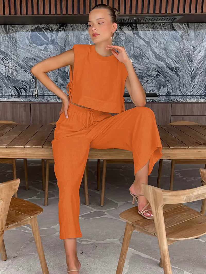 Woman in an orange outfit sitting at a wooden table with a marble wall in the background