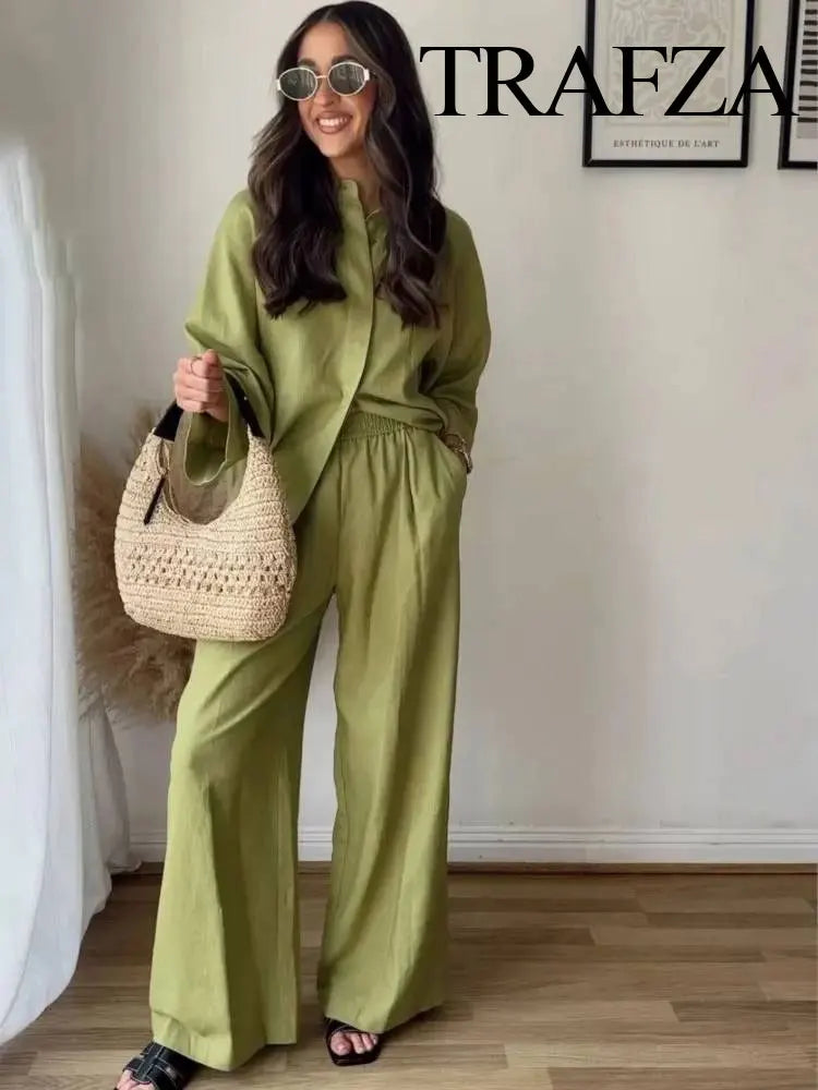 Woman in a green outfit holding a beige bag indoors with 'Trafza' branding.