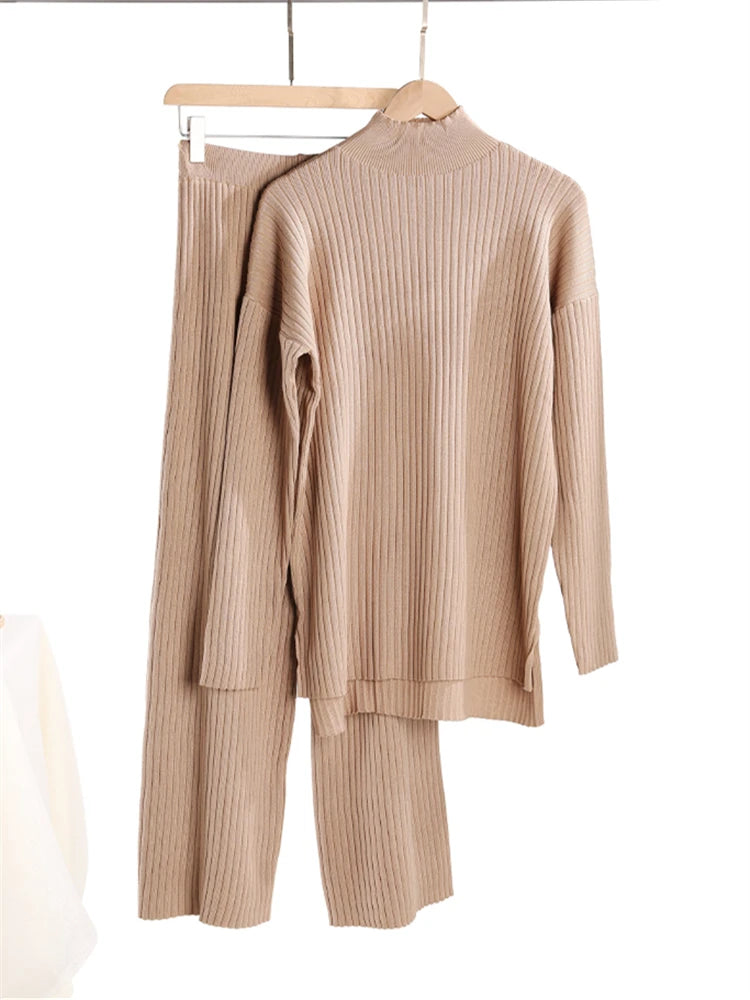 Beige ribbed sweater and pants set on hangers against a white background