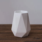 White geometric vase on a wooden surface with a plain background