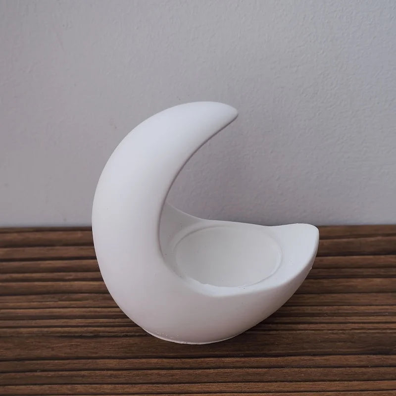 White ceramic crescent moon on a wooden surface with a plain background