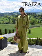 Woman in a green outfit holding a bag with a scenic background, featuring the brand 'Trafza'.