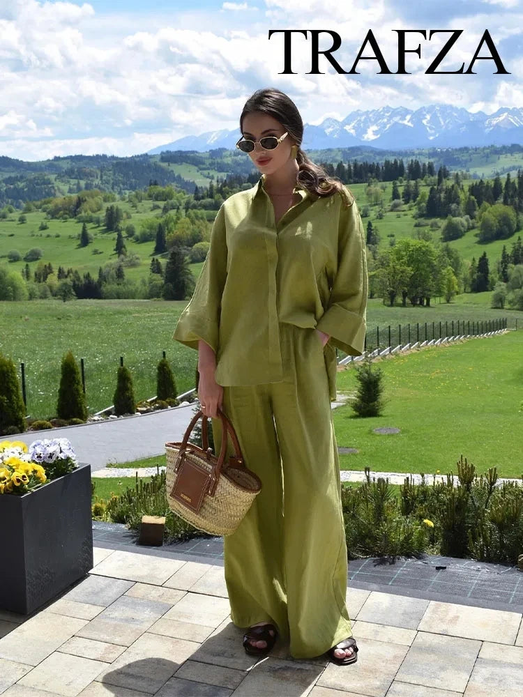 Woman in a green outfit holding a bag with a scenic background, featuring the brand 'Trafza'.