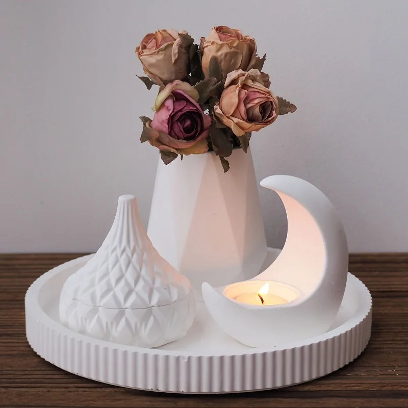 Decorative ceramic set with flowers, candle, and decorative items on a wooden surface.