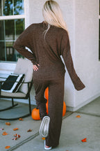 Person wearing a brown outfit standing on a patio with pumpkins and outdoor furniture.
