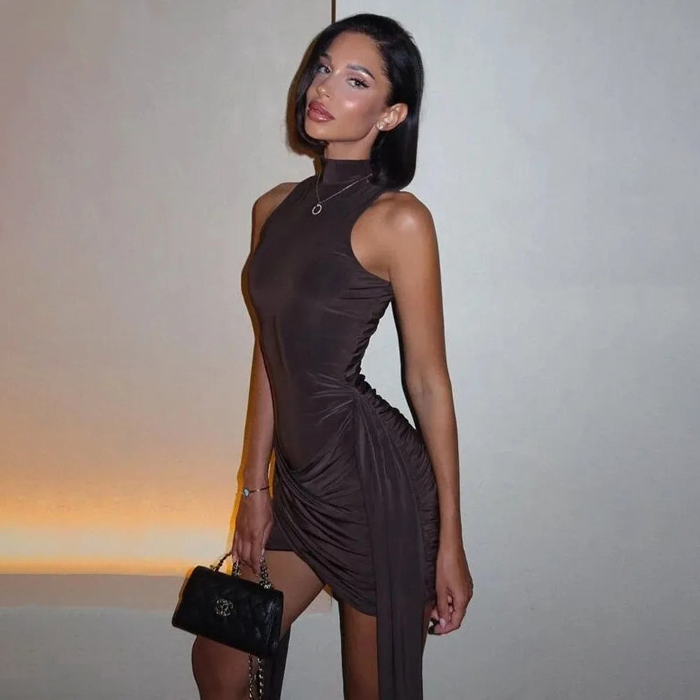 Woman in a brown dress holding a black handbag against a neutral background