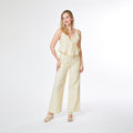 Woman wearing a light yellow ruffled top and wide-leg pants on a white background