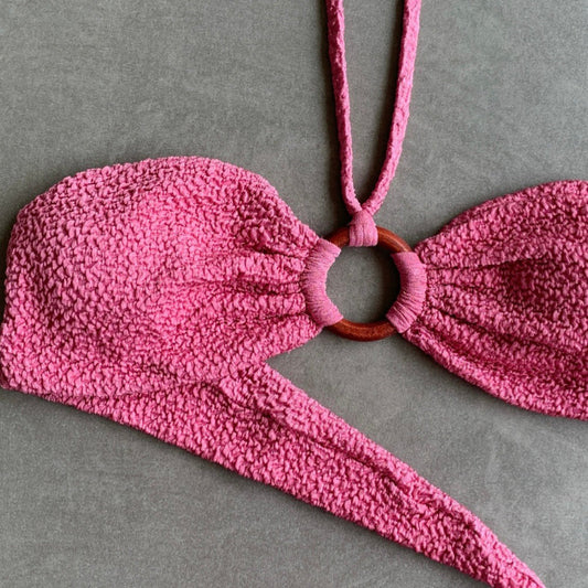 Pink textured bikini top on a gray background