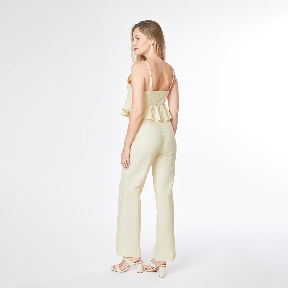 Woman wearing a light green jumpsuit with a peplum top on a white background