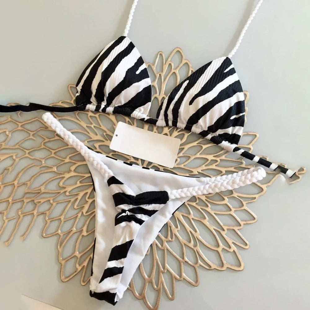 Black and white striped bikini set on a decorative gold stand against a light background