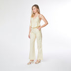 Woman wearing a light yellow jumpsuit on a white background