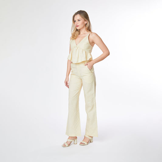 Woman wearing a light yellow jumpsuit on a white background