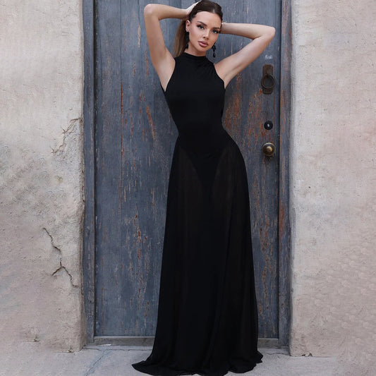 Woman in a black dress standing against a textured wall.