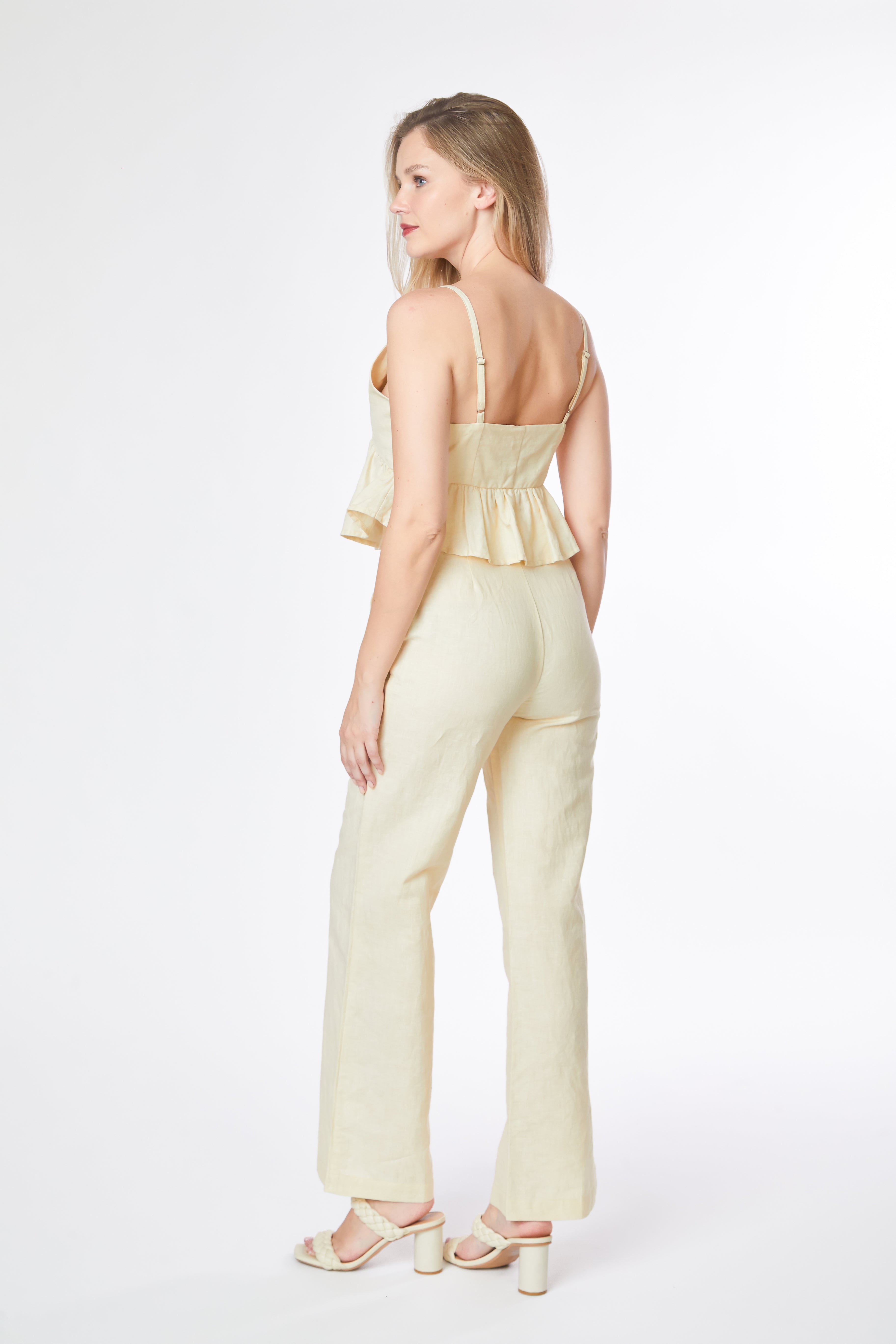 Woman wearing a light yellow jumpsuit on a white background