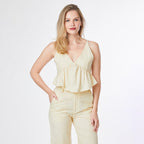 Woman wearing a light yellow sleeveless top and pants on a white background